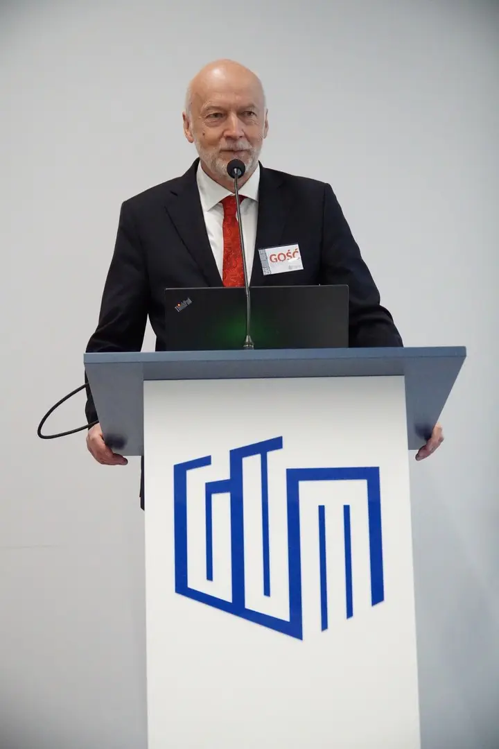 A speaker presenting at the lectern of the Central Office of Measures (GUM).
